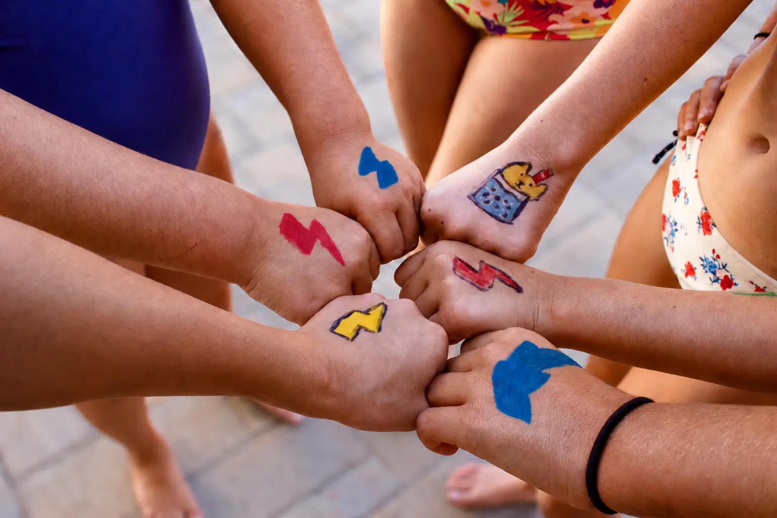 A group of swimmers showing colorful drawings on their hands